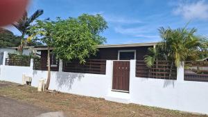 a house with a white wall and a tree at La Case in Rémiré