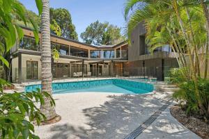 Noosa Retreat. Ocean Views, Pool and Serenity في نوسا هيدز: اطلالة خارجية على منزل به مسبح و نخيل