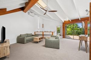 Noosa Retreat. Ocean Views, Pool and Serenity في نوسا هيدز: غرفة معيشة مفتوحة مع أريكة وتلفزيون
