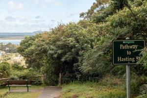 Noosa Retreat. Ocean Views, Pool and Serenity في نوسا هيدز: علامة مكتوب عليها شارع تحميص السكك الحديدية بجوار مقعد