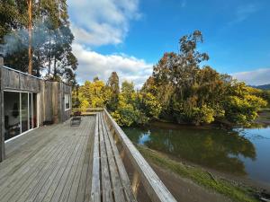 Un puente de madera sobre un río con un edificio. en House in the Maule River Bay, en Constitución