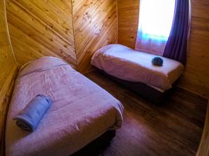 a room with two beds in a wooden room at Cabañas Aguapiedras in Linares