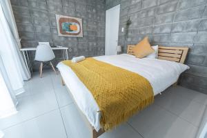 a bedroom with a large bed with a yellow blanket at Hale Twelve AB in Miyako-jima