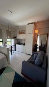 Una sala de estar con un sofá azul y una cocina. en Studio Caxambu MG, en Caxambu