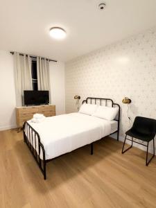 um quarto com uma grande cama branca e uma cadeira em The View - Direct Bus Time Square NYC Breakfast Included - A em Jersey City