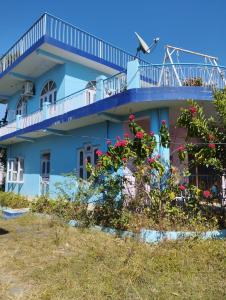 a blue house with a balcony and flowers at Pinewood Retreat in Bilāspur