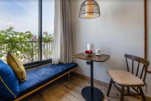 um quarto com um sofá azul e uma janela com uma mesa em Riverside Seahorse Danang Hotel em Da Nang