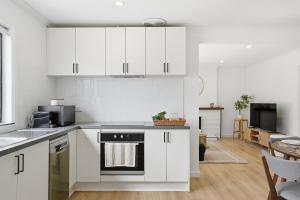 WarraneHobart Family Home near Airport & City的厨房配有白色橱柜和炉灶烤箱