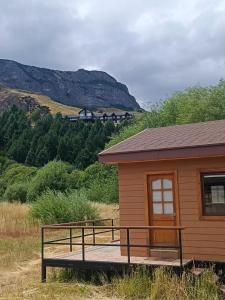 een kleine hut met een bank in een veld bij CABAÑA CON ACCESO A RIO in Coihaique