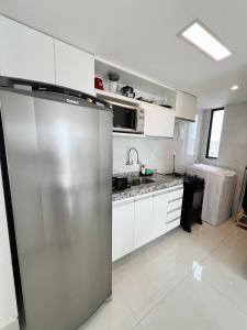 a kitchen with a stainless steel refrigerator and white cabinets at Cobertura Ponta Verde Vistar Mar in Maceió