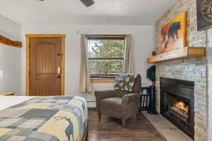 een slaapkamer met een open haard en een bed en een stoel bij Cabin15 - King bed Hotel Style Unit in Estes Park