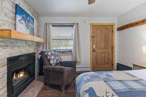 een slaapkamer met een open haard en een bed en een stoel bij Cabin16 - King Bed Kitchenette & Bath in Estes Park