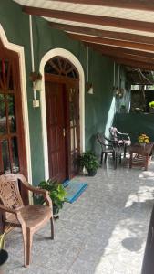 a green building with chairs and a wooden door at Mango paradise sigiriya in Dambulla