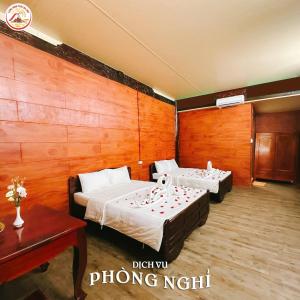 Làng Du Lịch Sinh Thái Đá Nổi في Phong Ðiền: غرفة نوم بها سريرين وجدار خشبي +صورة واحدة