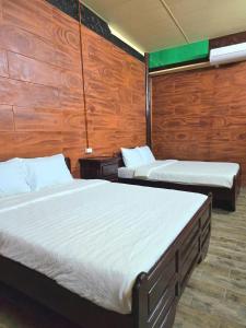 Làng Du Lịch Sinh Thái Đá Nổi في Phong Ðiền: سريرين في غرفة مع ألواح خشبية