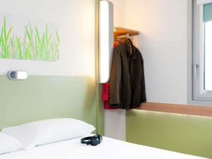 a room with a bed with a mirror and a coat at ibis budget Beaconsfield in Beaconsfield