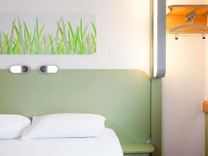 Un dormitorio con una cama con una pintura de plantas en la pared. en ibis budget Beaconsfield, en Beaconsfield 25 fotos más
