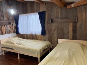 two beds in a room with a window at Toma House in Tōma
