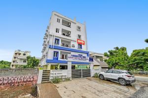 un bâtiment blanc avec une voiture garée devant dans l'établissement Hotel O Coastal Inn Luxury Service Apartments, à Kakinada