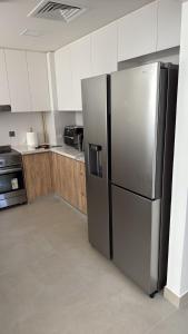 a kitchen with a stainless steel refrigerator and wooden cabinets at Noya Viva villa in Abu Dhabi