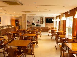 a restaurant with wooden tables and chairs and a kitchen at ibis Vitoria da Conquista in Vitória da Conquista