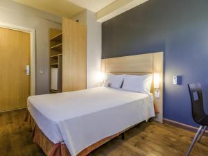 a large white bed in a room with a chair at ibis Barretos in Barretos