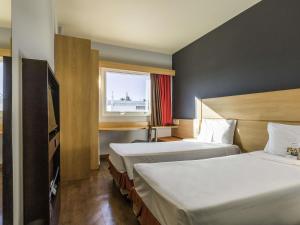 a hotel room with two beds and a window at ibis Barretos in Barretos