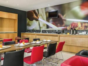 a dining room with a table and red chairs at ibis Barretos in Barretos