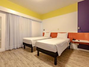 two beds in a room with yellow and purple at Ibis Styles Balneário Camboriú - 1 Quadra do Mar in Balneário Camboriú +52 photos