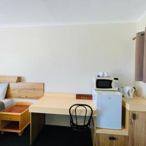 a room with a desk with a microwave and a refrigerator at Wee Waa Motel in Wee Waa