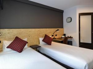 una camera d'albergo con due letti e una scrivania di ibis budget Sydney East a Sydney