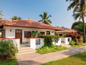 a white house with palm trees in front of it at Novotel Goa Dona Sylvia Resort in Cavelossim +175 photos