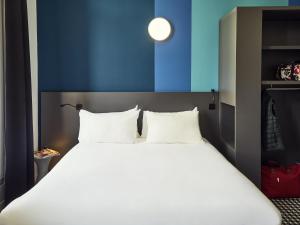 Cette chambre comprend un grand lit blanc et un mur bleu. dans l'établissement ibis Styles Marseille Vieux Port, à Marseille