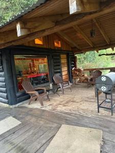 Santa Bárbaracabañas refugio quillaileo的一个带椅子和烧烤架的小屋门廊
