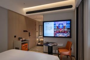 FunGee X Hotel 长沙国金中心南门口地铁站店 في تشانغشا: غرفة فندق مع شاشة كبيرة على الحائط