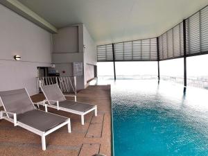 a swimming pool with two chairs in a building at Mercure Selangor Selayang in Batu Caves