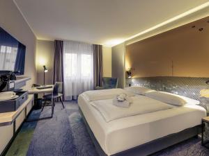 a hotel room with a large bed and a desk at Mercure Stuttgart Zuffenhausen in Stuttgart