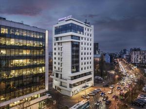 a tall white building with a sign on top of it at Mercure Bucharest Unirii in Bucharest