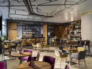 un restaurant avec des tables et des chaises et un bar dans l'établissement Mercure Bucharest Unirii, à Bucarest