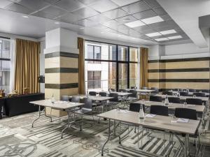 une salle à manger avec tables, chaises et fenêtres dans l'établissement Mercure Bucharest Unirii, à Bucarest