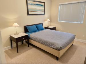 a bedroom with a bed with blue pillows and a window at Urban Chic residence in Central LA in Los Angeles