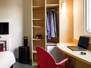 a room with a desk with a laptop and a red chair at ibis Marilia in Marília +83 photos