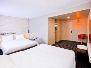 a hotel room with two beds and a red chair at ibis Styles Chalons en Champagne Centre in Chalons en Champagne
