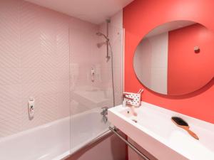 une salle de bain avec une baignoire, un lavabo et un miroir dans l'établissement ibis Styles Chalons en Champagne Centre, à Châlons-en-Champagne 70 autres photos