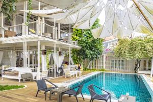 a swimming pool with chairs and a building at To The Moon Guesthouse in Chiang Mai