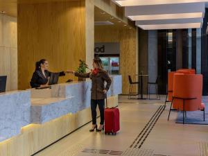 a woman with a suitcase standing at a counter in an airport at Mercure Sao Paulo Barra Funda in Sao Paulo