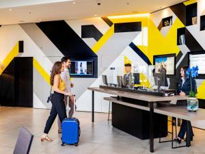 two people walking with a suitcase in a lobby at Novotel Sorocaba in Sorocaba
