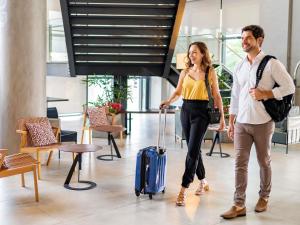 a man and a woman walking with a suitcase at Novotel Sorocaba in Sorocaba