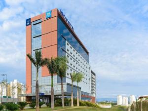 a hotel with palm trees in front of a building at Novotel Sorocaba in Sorocaba