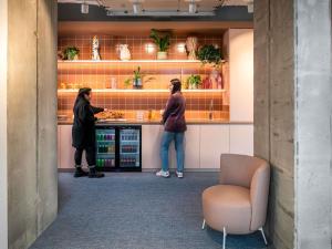 zwei Leute stehen an einem Tresen in einem Laden in der Unterkunft ibis budget Gent Centrum Dampoort in Gent